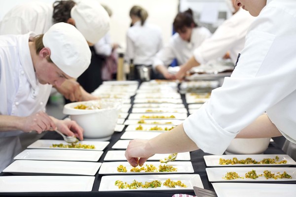 Student chefs plating up salmon and prawn boudin with vege cous cous and Heart of the Desert saffron foam